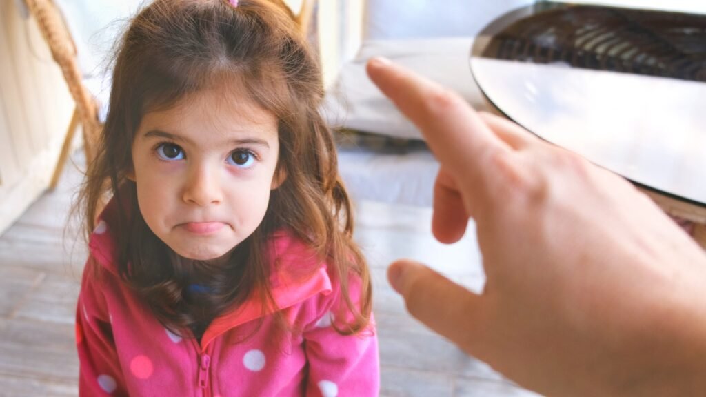 A young girl looking up as an adult points at her