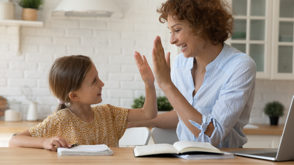 A child and a parent sharing a high five over homework